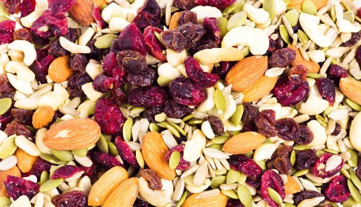 Assorted trail mix with nuts, dried fruits, and seeds in a bowl.