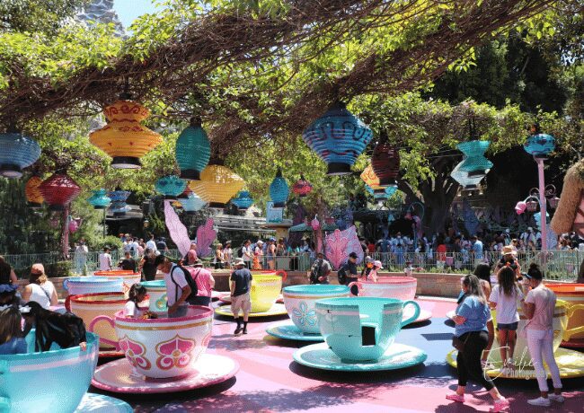 The vibrant Mad Hatter's hat and oversized teapots create a whimsical backdrop, while the joyful laughter of guests fills the air.