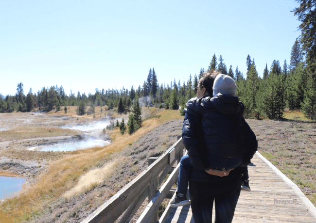 Just me and my little one, leisurely strolling through the captivating Thumb Geyser Area, taking in the unique sights and feeling the excitement of nature's bubbling geysers all around us.