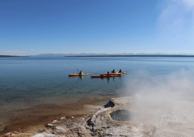 Tourists enjoy kayaking and exploring the tranquil waters surrounded by the breathtaking natural beauty of the Yellowstone Lake.