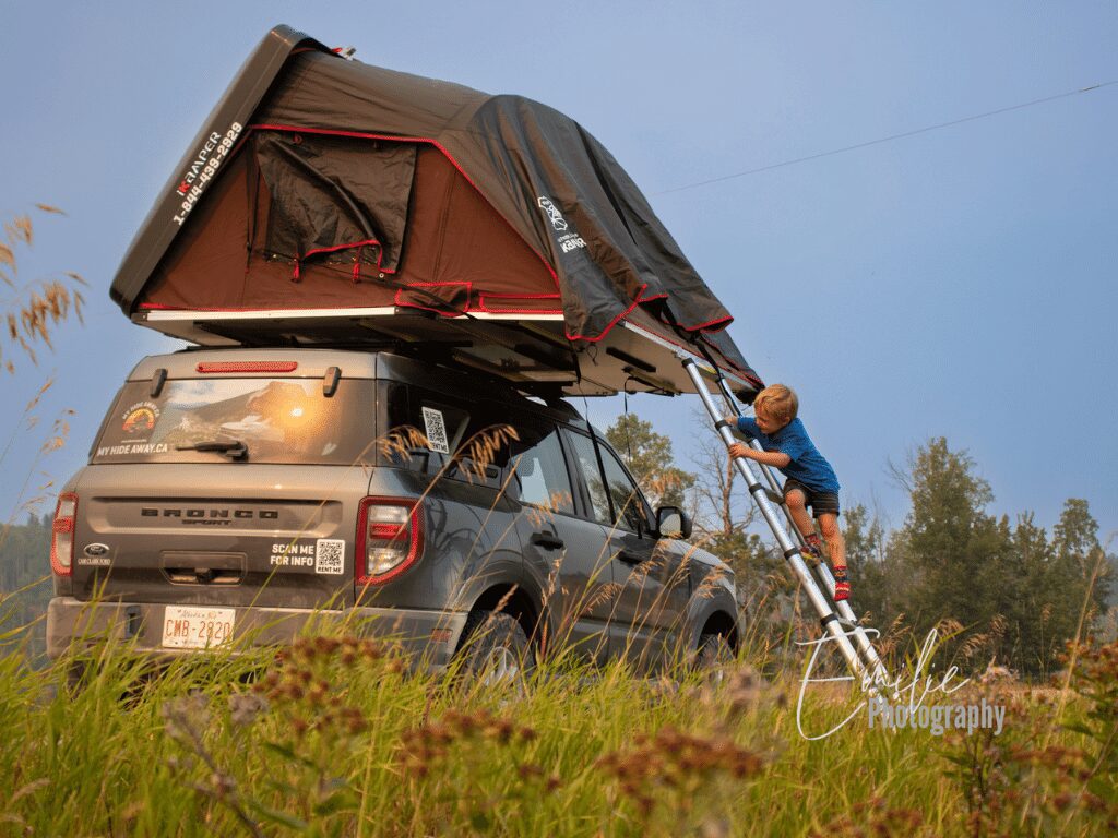 Discover the thrill of camping with a car rooftop tent near Calgary. Experience the convenience and comfort of elevated camping as the young boy eagerly sets up the tent, a symbol of his budding outdoor skills and independence.