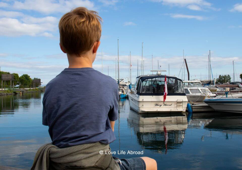 Enjoying Prince Arthurs Landing in Thunder Bay. A kid sitting on a bench looking at boats at the marina in Thunder Bay.
