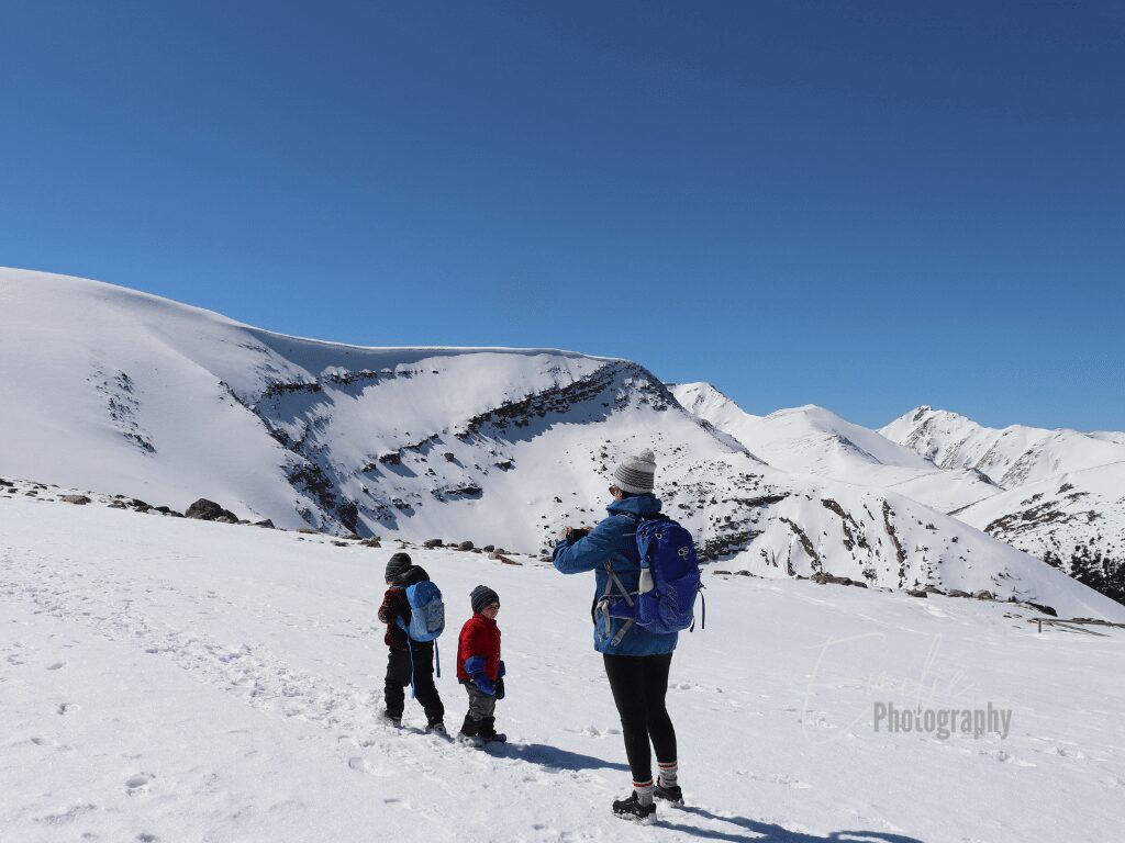 a family hiking in the winter. They are wear the right winter hiking gear
