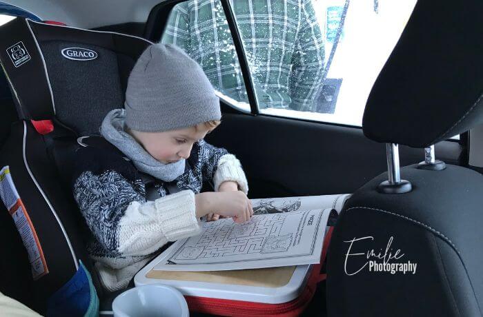 One of the road trip essentials when traveling with kids is packing a coloring book. My son coloring his book while on the road.