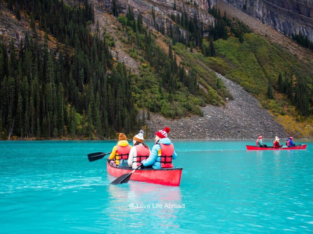 Three women on a canoe in the middle of Lake Louise.