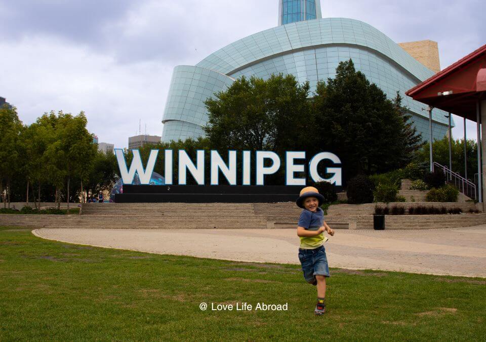 Kid running away from the Winnipeg sign